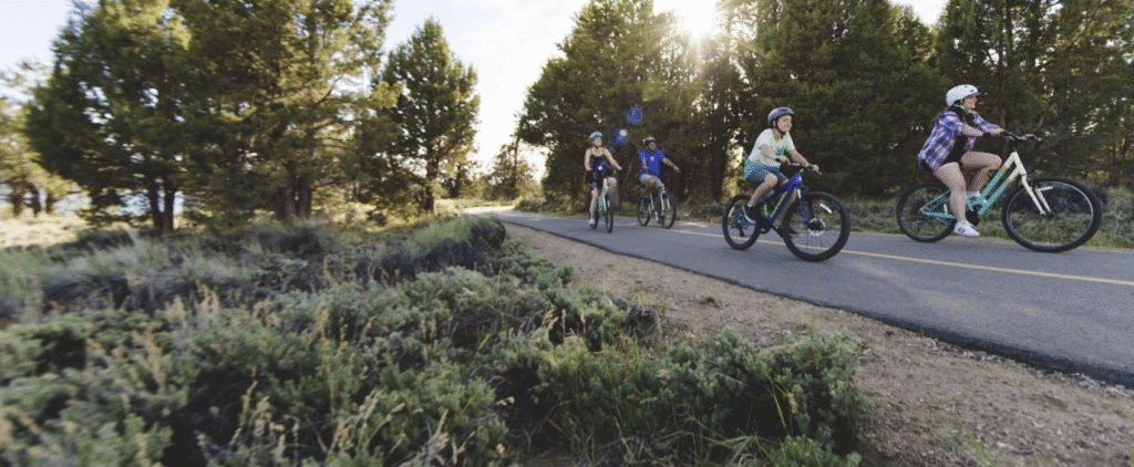 Family riding bikes on a paved path in Big Bear Lake rented from Big Bear Bike Rentals