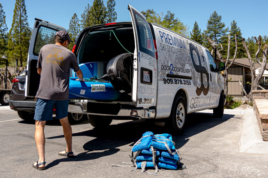 Getboards employee loading a kayak into the back of a delivery van for a Big Bear Kayak Rentals customer